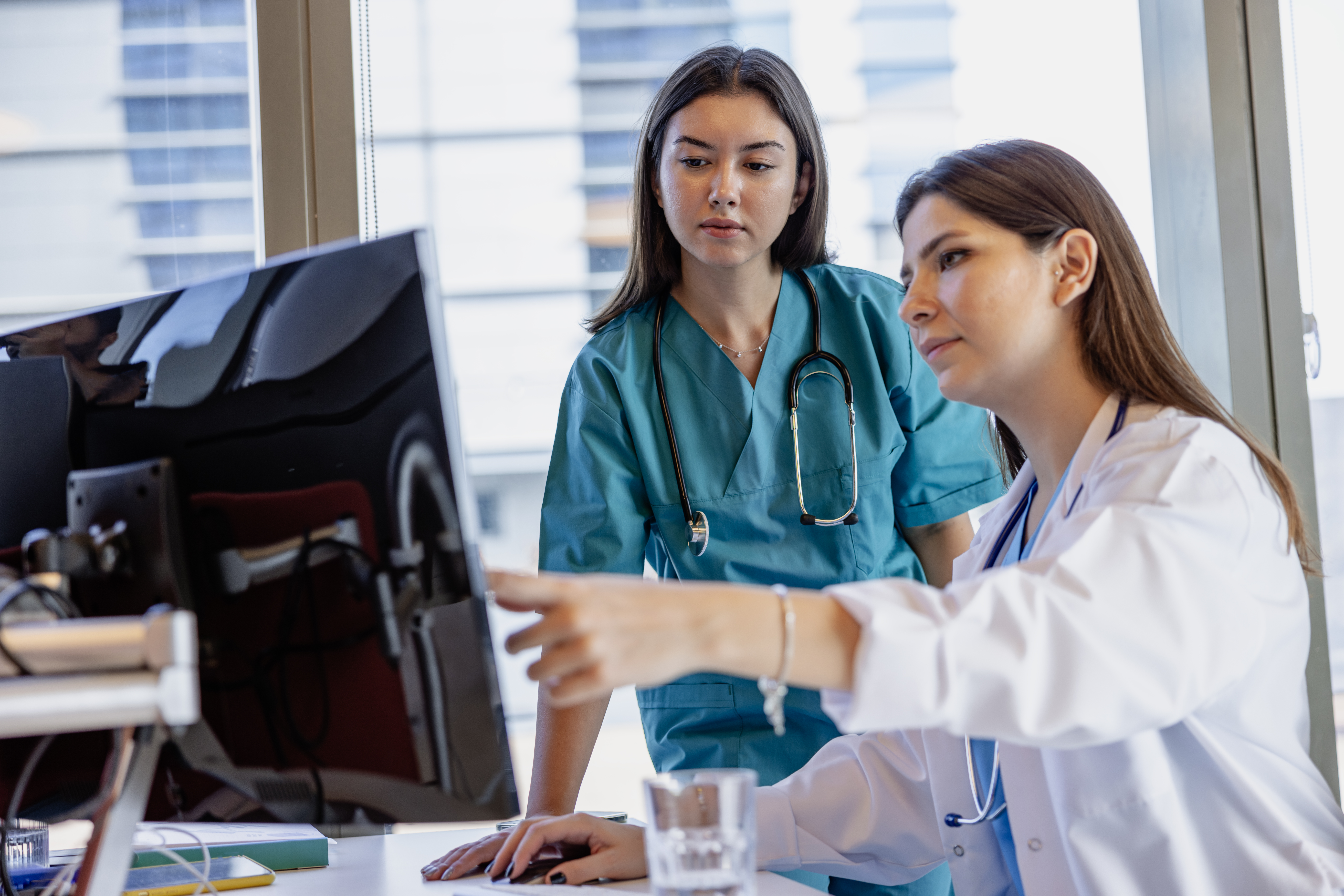 Two healthcare professional women are working on the computer